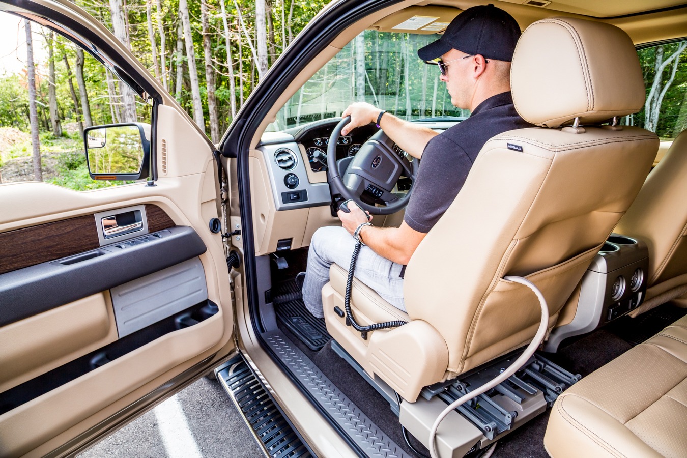 A man sittting in the driver's seat of a Ford F-150 holding the LINK pendant in left hand and gripping steering wheel in right hand. (over the shoulder)