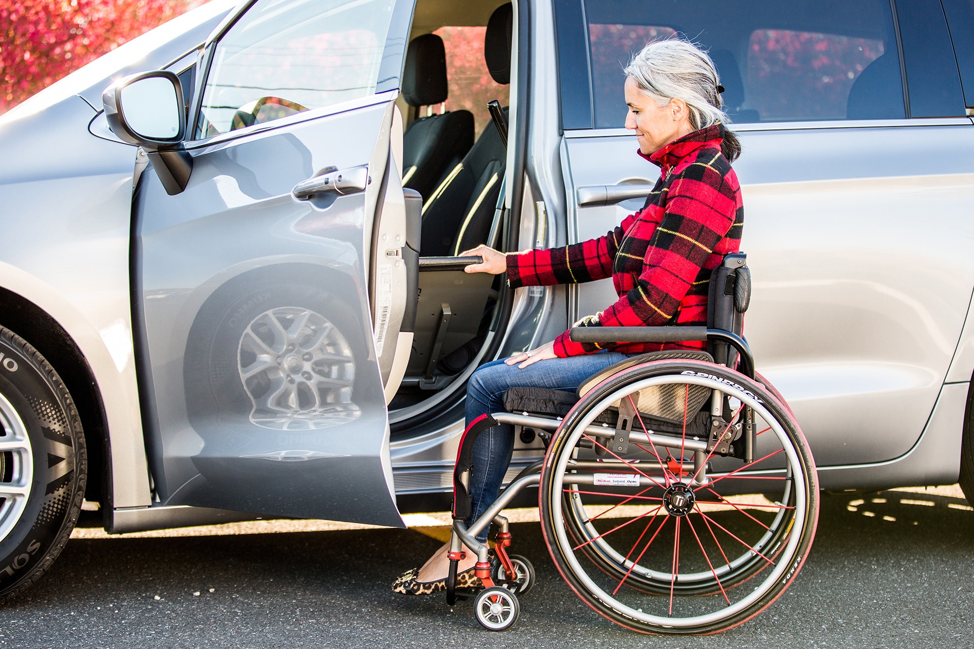 A woman flipping the transfer board of the ASENTO down while sitting in a ridgid frame manual wheelchair. (door half open)