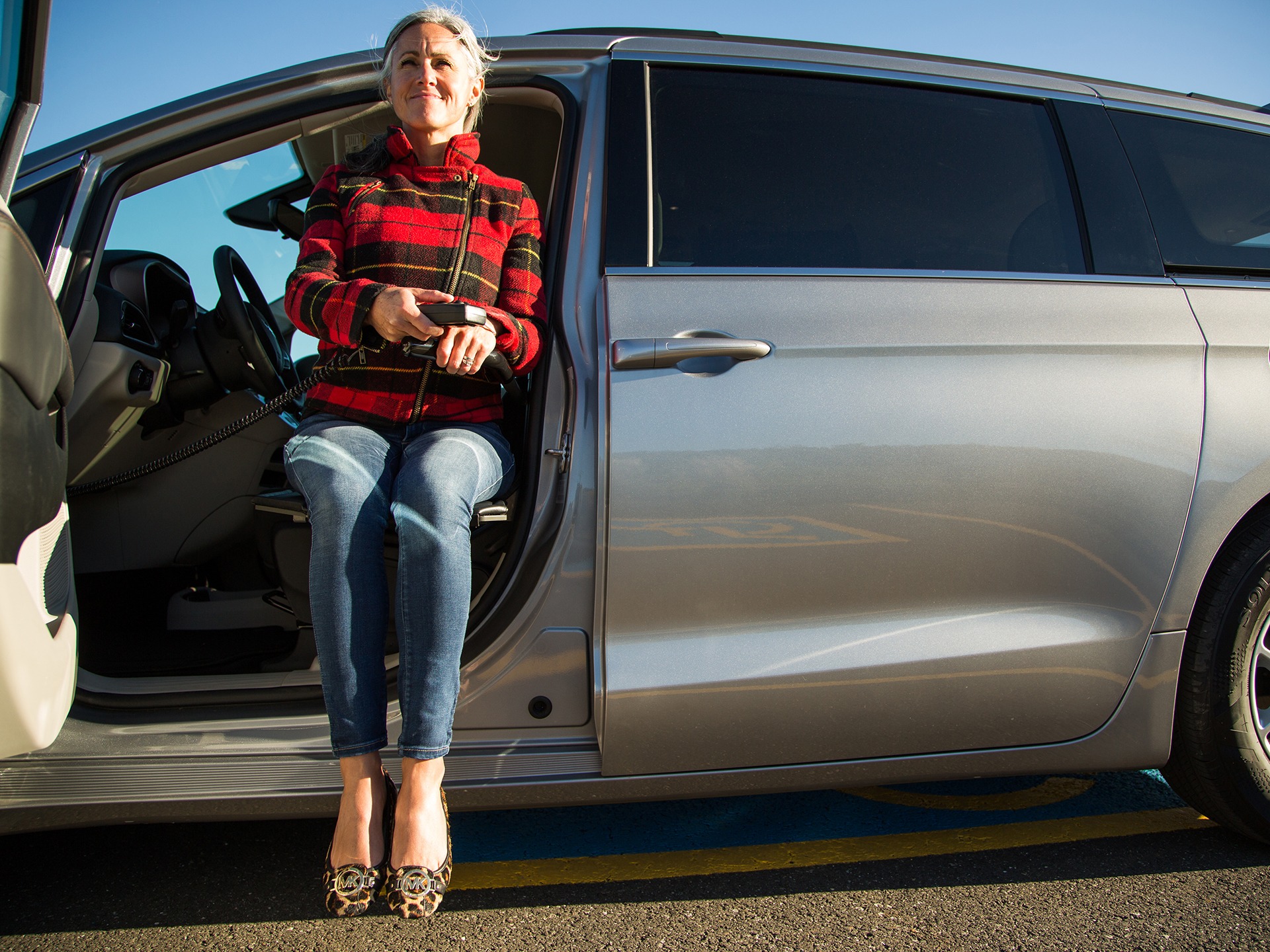 A woman sits on an ASENTO level with and perpendicular to the OEM seat of a Chyrsler Pacifica
