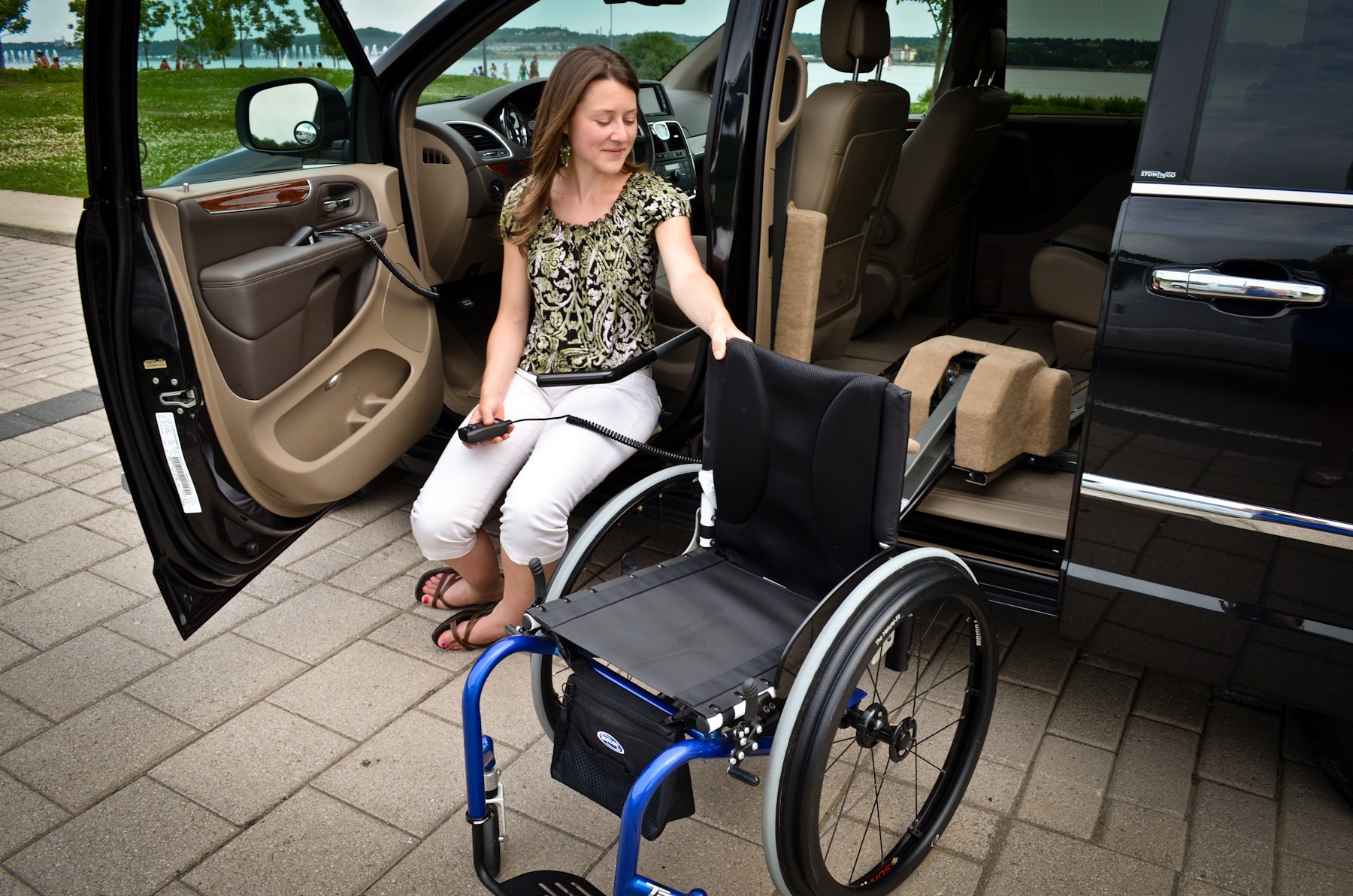 A woman is guiding her rigid-frame manual wheelchair onto the SPEEDY-LIFT.